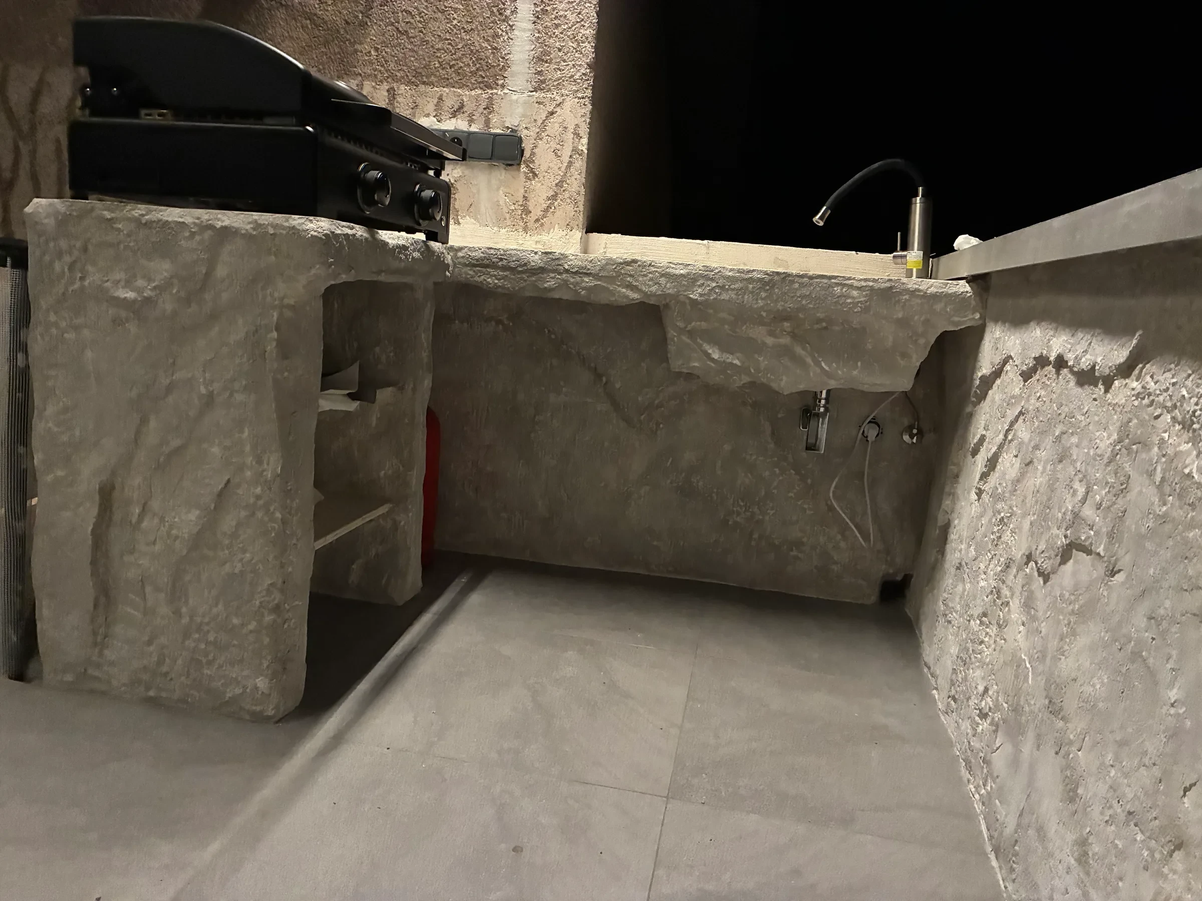 Baterie u&nbsp;kamenného dřezu při večerním osvětlení